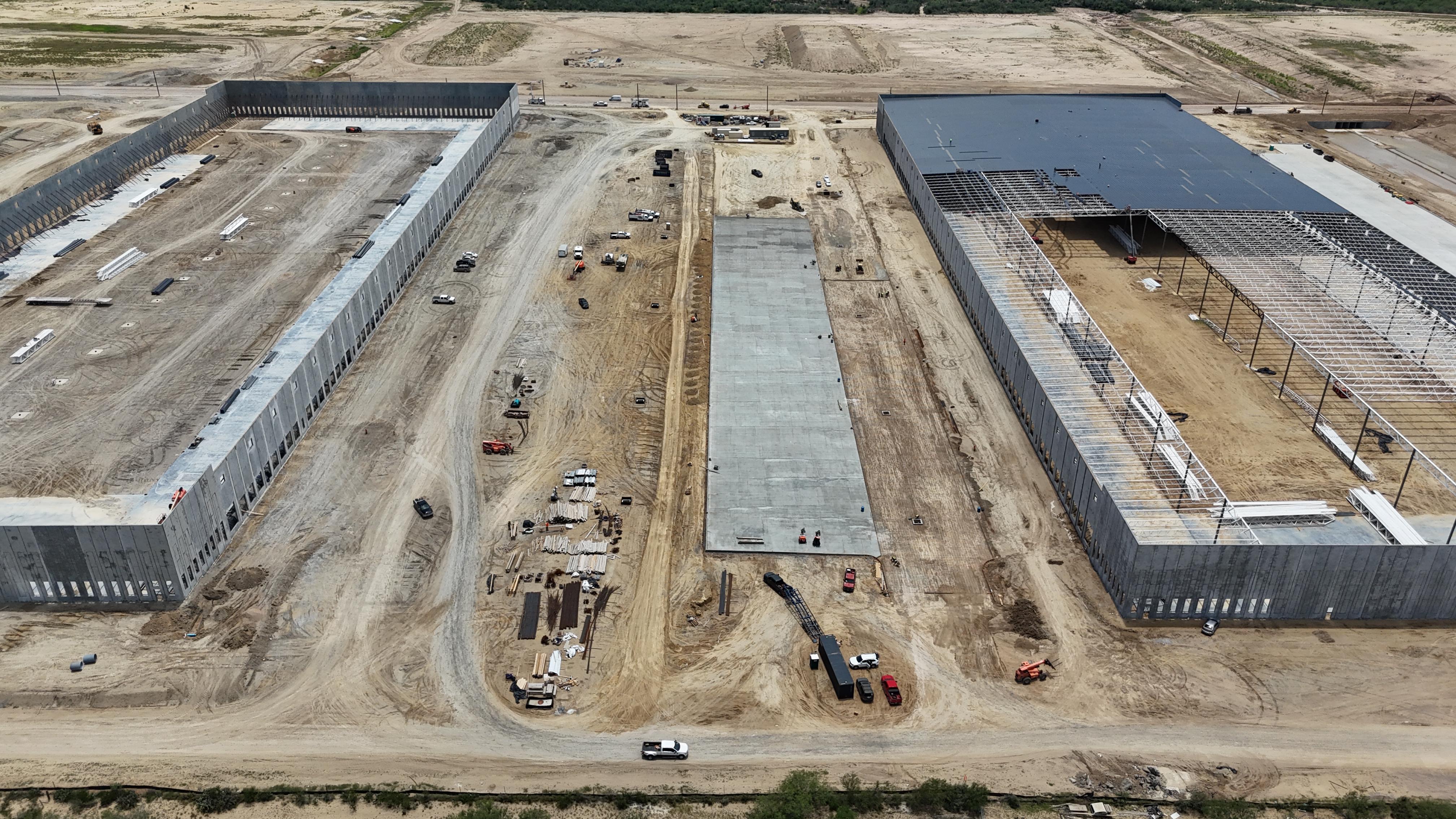 Aerial view of two large industrial buildings with a concrete drive lane between them